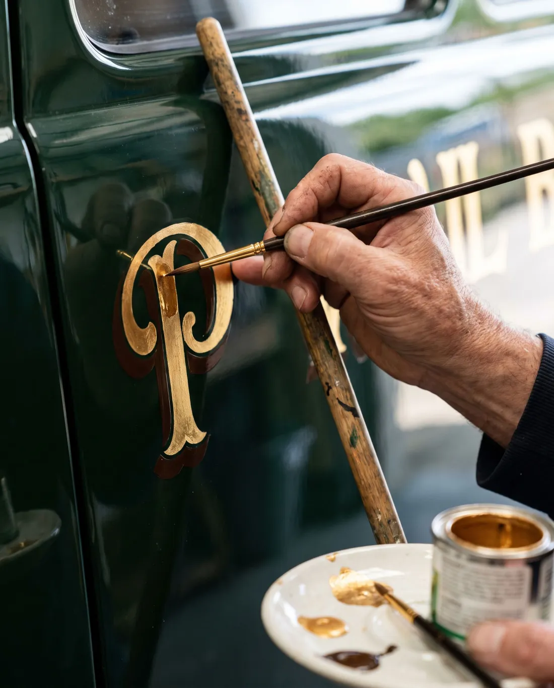 A signwriter painting gold lettering